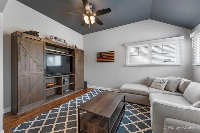 living room with ceiling fan, a barn door, baseboards, wood finished floors, and lofted ceiling