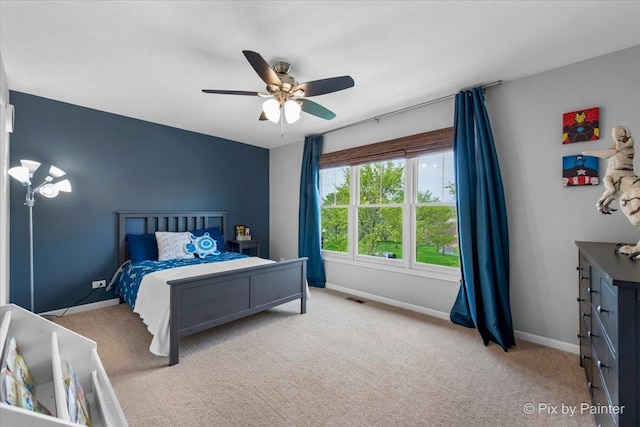 carpeted bedroom with baseboards, a ceiling fan, and visible vents