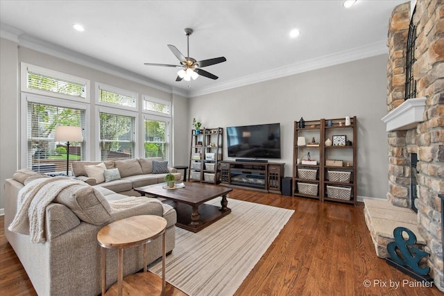 living room featuring ornamental molding, wood finished floors, a stone fireplace, ceiling fan, and recessed lighting
