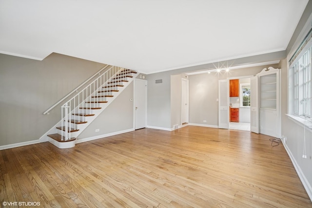 444 Winnetka Ave, Winnetka, IL 60093 - unfurnished living room with stairs, light wood-type flooring, ornamental molding, and baseboards