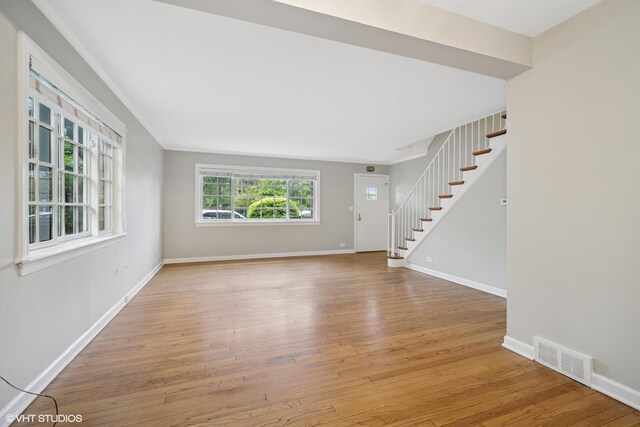 444 Winnetka Ave, Winnetka, IL 60093 - unfurnished living room with stairs, light wood-type flooring, and baseboards