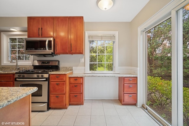444 Winnetka Ave, Winnetka, IL 60093 - kitchen with appliances with stainless steel finishes, a sink, a wainscoted wall, light stone countertops, and light tile patterned flooring