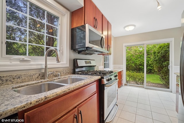 444 Winnetka Ave, Winnetka, IL 60093 - kitchen featuring stainless steel appliances, a sink, wainscoting, light tile patterned floors, and light stone countertops