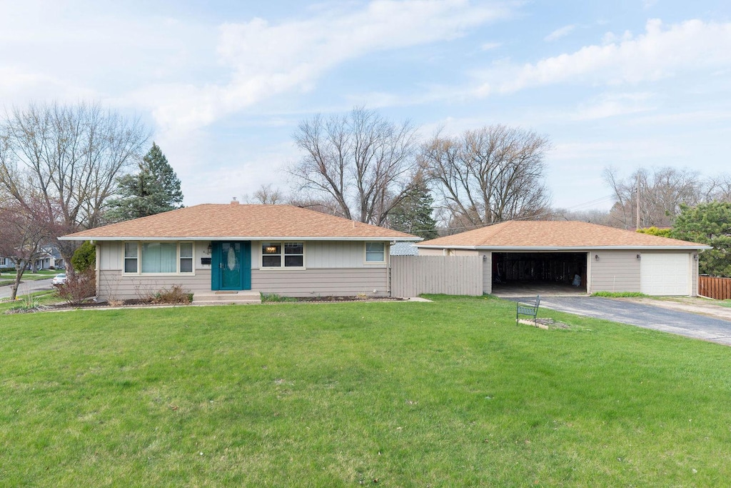 ranch-style house with an outdoor structure, fence, a garage, entry steps, and a front lawn