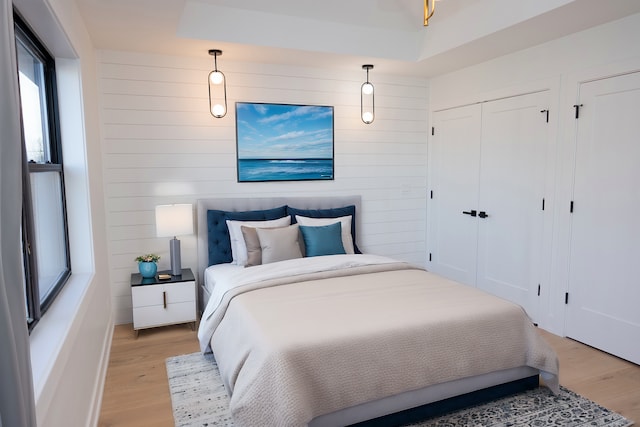bedroom featuring light wood-type flooring, wood walls, and baseboards