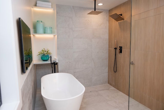 bathroom with a walk in shower, a freestanding tub, and tile walls