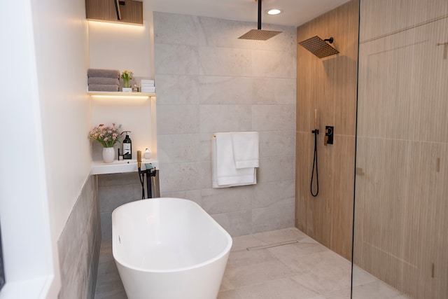 bathroom featuring a walk in shower, a freestanding bath, and tile walls