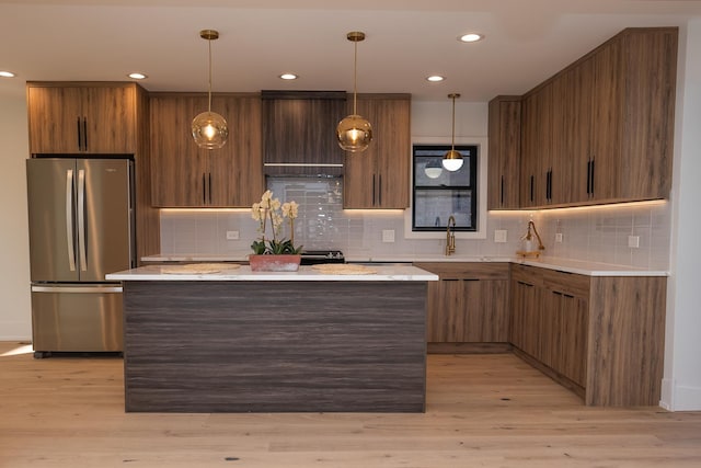 kitchen with freestanding refrigerator, tasteful backsplash, a sink, and light countertops