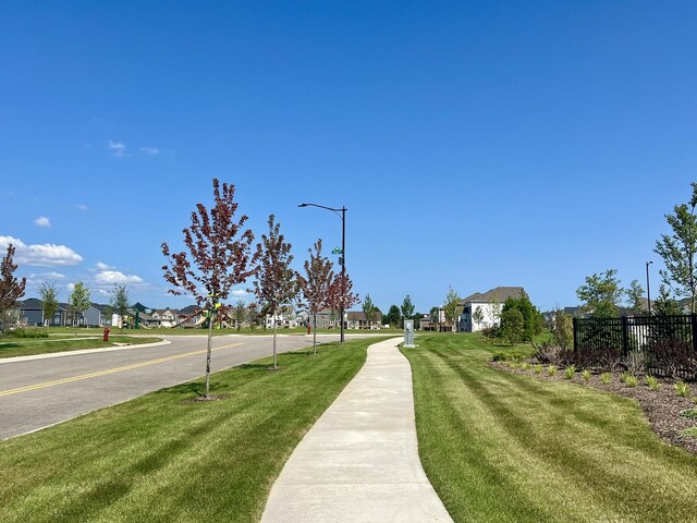 view of community with a lawn, fence, and a residential view