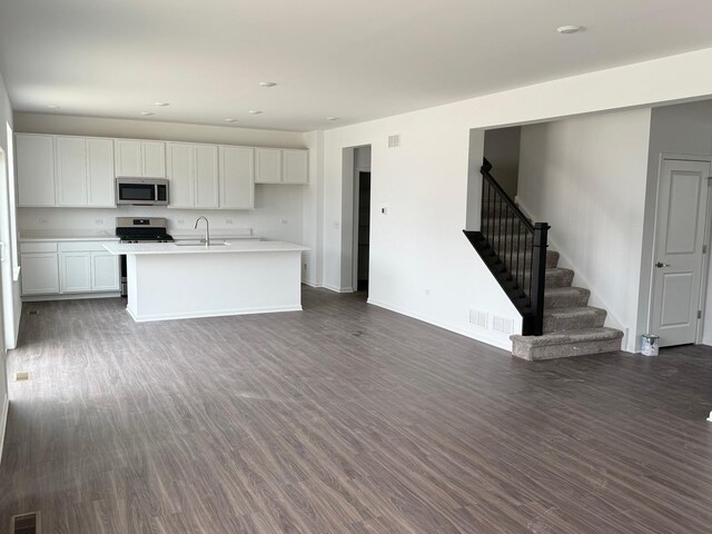 kitchen with stainless steel appliances, light countertops, dark wood-style floors, and a sink