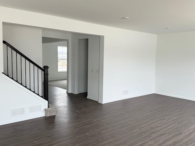 unfurnished room with visible vents, baseboards, and dark wood-type flooring