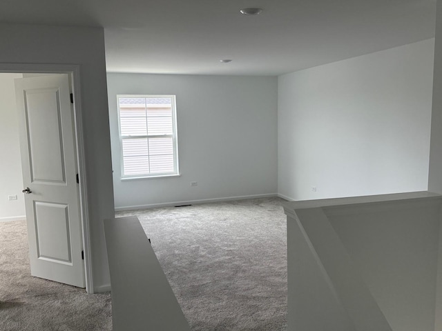 unfurnished room featuring baseboards, visible vents, and carpet