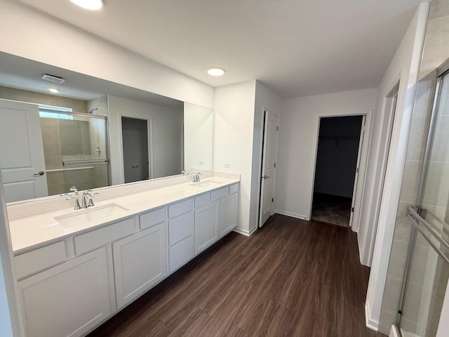 bathroom featuring a stall shower, double vanity, a sink, and wood finished floors