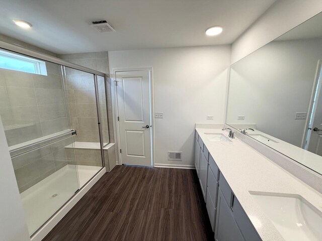 full bathroom with a sink, visible vents, a shower stall, and wood finished floors