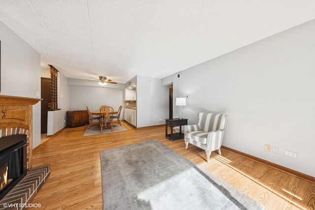 sitting room with light wood-type flooring, a ceiling fan, visible vents, and a fireplace