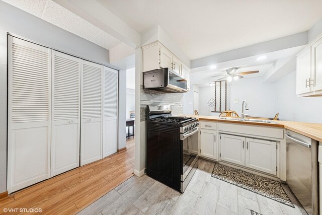 kitchen featuring ceiling fan, a sink, stainless steel appliances, a peninsula, and light wood-type flooring