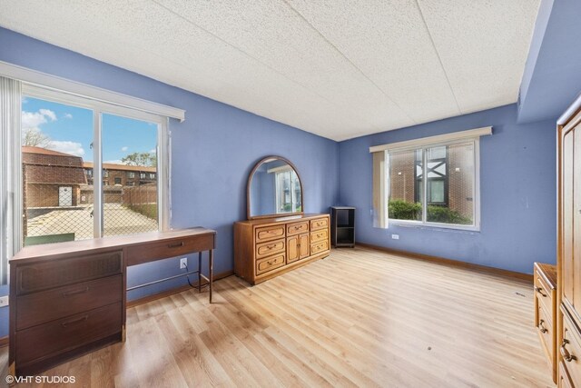bedroom featuring baseboards, wood finished floors, and multiple windows