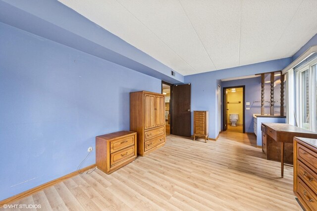 unfurnished bedroom featuring visible vents, connected bathroom, light wood finished floors, and baseboards