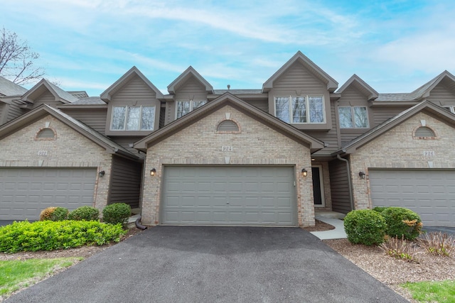 view of property featuring brick siding, driveway, and a garage