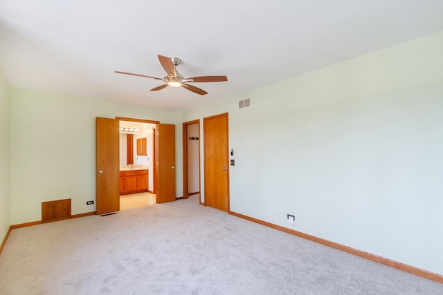 unfurnished bedroom featuring visible vents, baseboards, light colored carpet, a ceiling fan, and ensuite bath