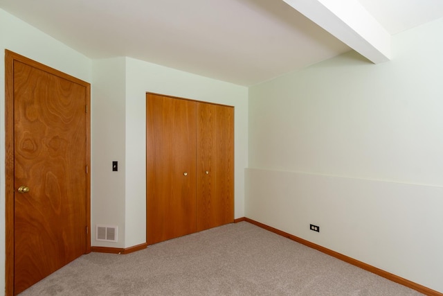 unfurnished bedroom featuring carpet flooring, baseboards, visible vents, and a closet