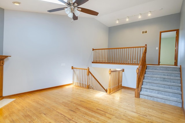 stairway featuring a ceiling fan, baseboards, wood finished floors, lofted ceiling, and visible vents