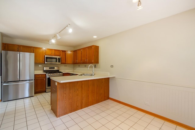 kitchen with brown cabinetry, a sink, light countertops, a peninsula, and stainless steel appliances