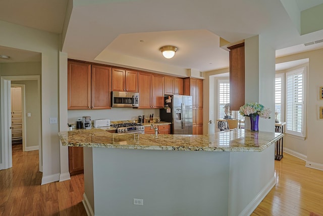kitchen featuring light stone countertops, brown cabinets, light wood-type flooring, visible vents, and appliances with stainless steel finishes