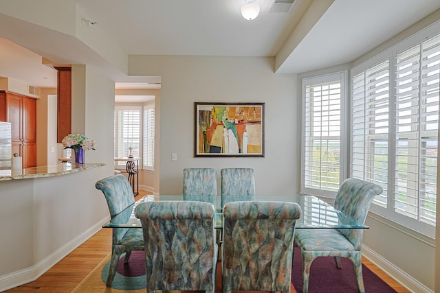 dining area featuring light wood-style floors, plenty of natural light, visible vents, and baseboards