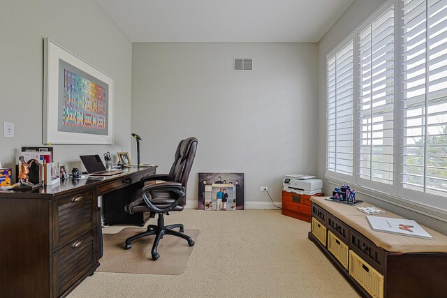 office area featuring visible vents, baseboards, light carpet, and plenty of natural light