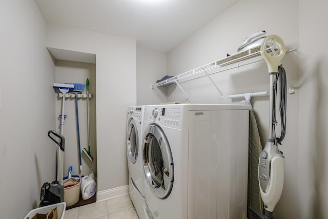 clothes washing area with light tile patterned flooring, baseboards, laundry area, and washer and clothes dryer