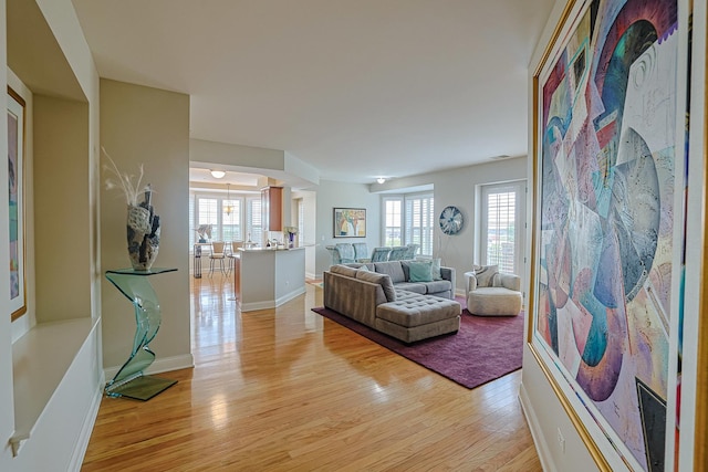 living area with light wood-style flooring, a wealth of natural light, and baseboards