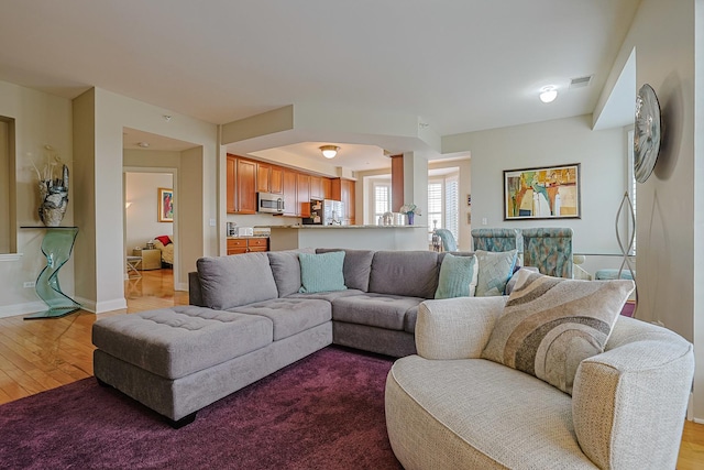 living room featuring baseboards, visible vents, and wood finished floors