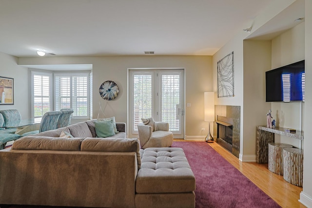 living area with a fireplace, visible vents, baseboards, and light wood-type flooring