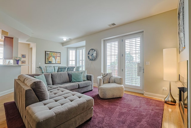 living room featuring baseboards, visible vents, and wood finished floors