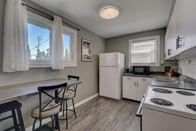 479 Oak St, Des Plaines, IL 60016 - kitchen featuring a sink, a kitchen breakfast bar, light wood-type flooring, white appliances, and white cabinets