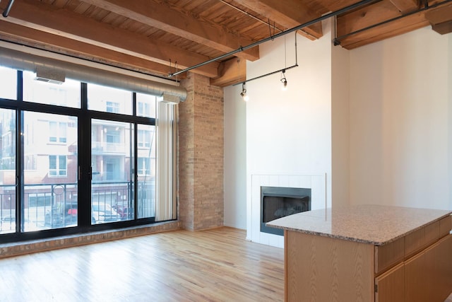 1250 W Van Buren St Unit 203, Chicago, IL 60607 - unfurnished living room with light wood-style flooring, a fireplace, wooden ceiling with exposed beams, and brick wall