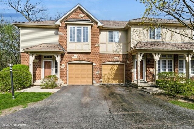 view of front of house featuring stucco siding, brick siding, a garage, and aphalt driveway