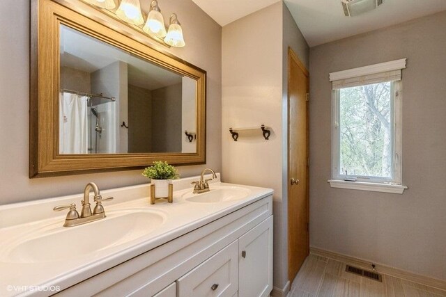 bathroom featuring double vanity, a sink, baseboards, and visible vents