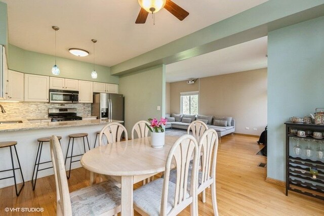 dining space featuring baseboards, a ceiling fan, and light wood-style flooring