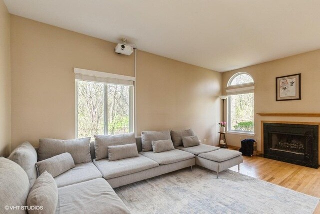 living room featuring a fireplace with flush hearth and wood finished floors