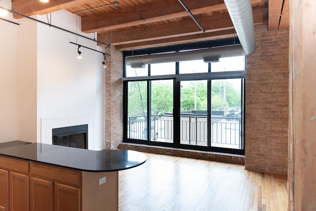 1250 W Van Buren St Unit 202, Chicago, IL 60607 - unfurnished living room featuring brick wall, wood finished floors, a fireplace, and wood ceiling with exposed beams