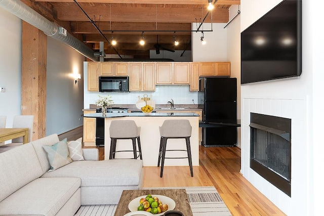 1250 W Van Buren St Unit 202, Chicago, IL 60607 - living area featuring track lighting, light wood-type flooring, a fireplace, and a towering ceiling