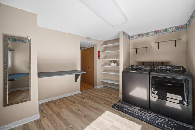 washroom featuring separate washer and dryer, laundry area, visible vents, and wood finished floors