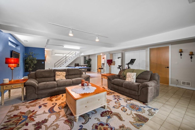 tiled living room with stairway, rail lighting, and visible vents
