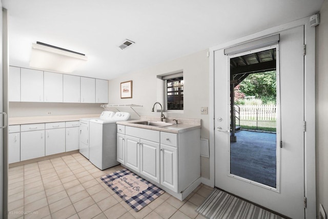 clothes washing area featuring cabinet space, washing machine and clothes dryer, a sink, light tile patterned floors, and visible vents