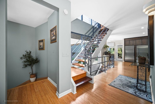 stairway with recessed lighting, baseboards, and wood finished floors