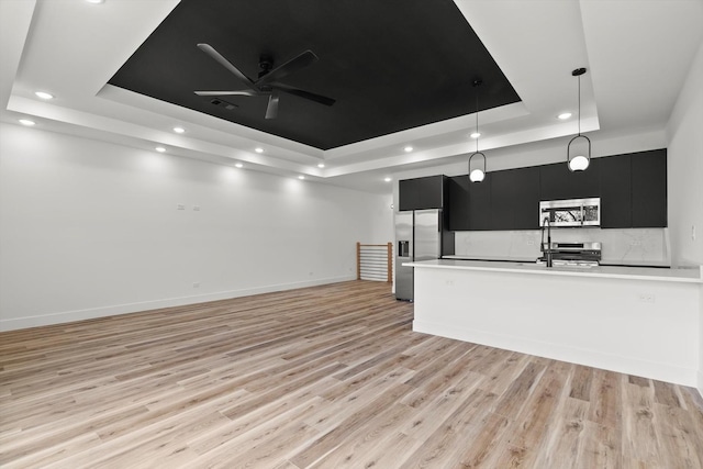 kitchen featuring appliances with stainless steel finishes, light countertops, dark cabinets, a tray ceiling, and recessed lighting