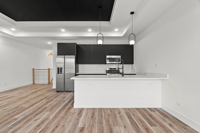 kitchen with light countertops, dark cabinets, stainless steel appliances, recessed lighting, and a tray ceiling