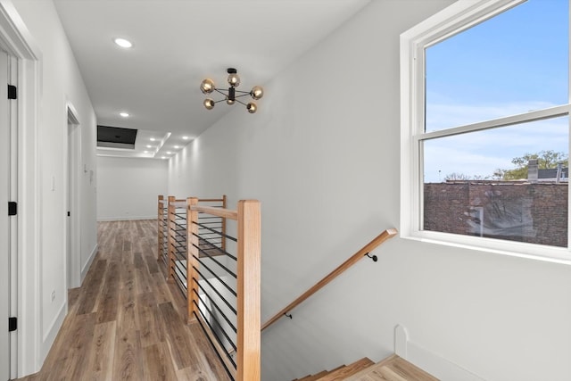 corridor with an upstairs landing, wood finished floors, baseboards, a chandelier, and recessed lighting